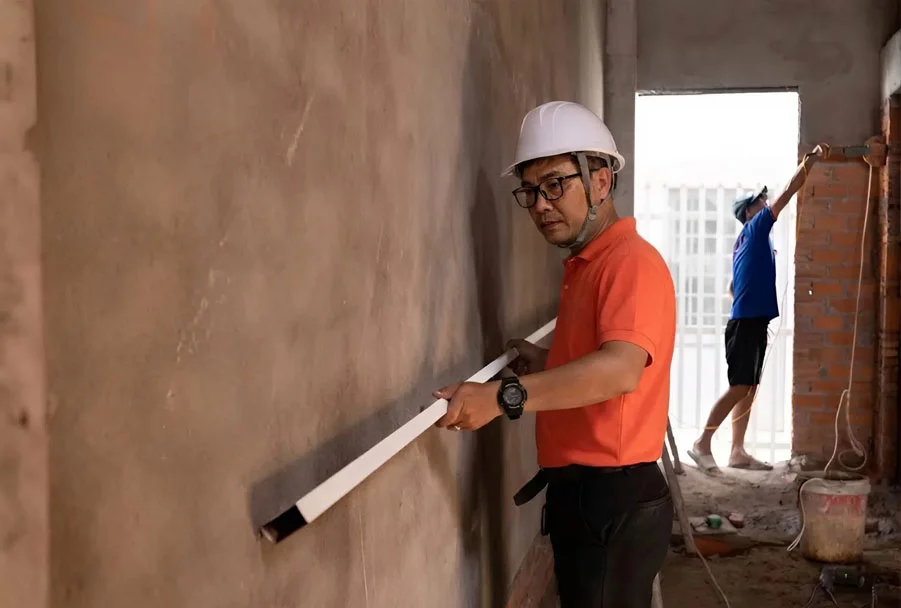 Kỹ sư kiểm tra độ thẳng đứng của tường th&ocirc; trước khi lắp đặt nội thất gỗ